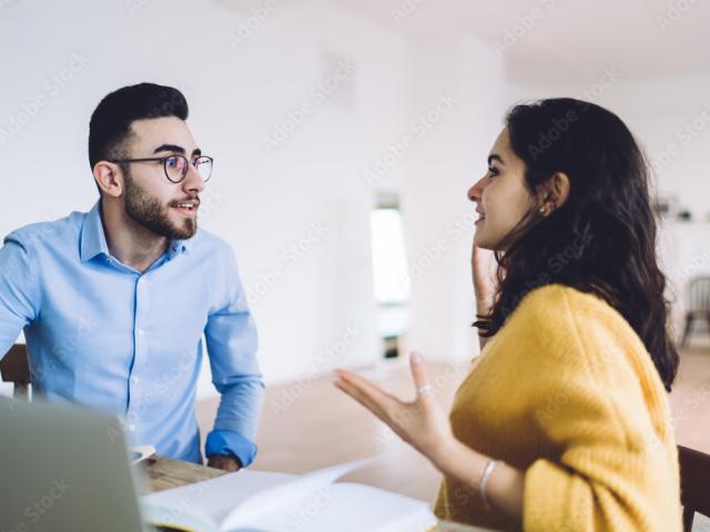 Jeune femme  et trentenaire discutant autour d'un ordinateur.