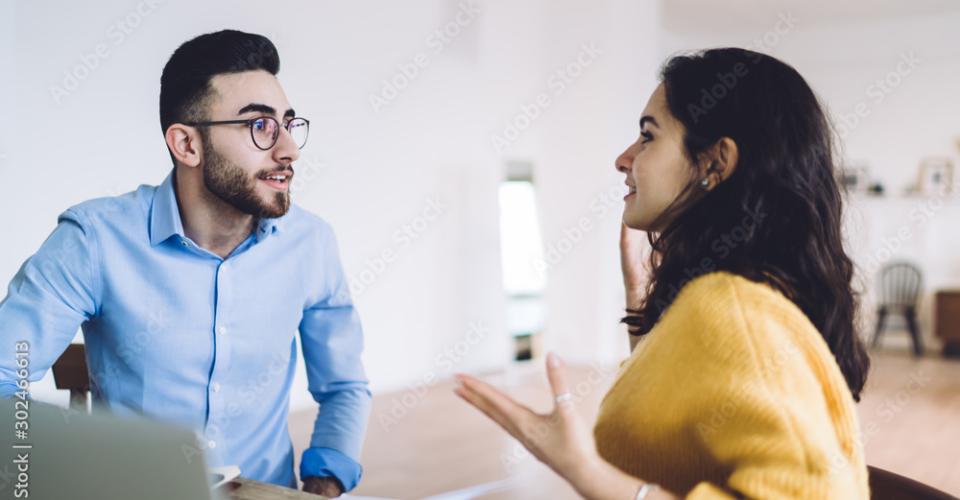 Jeune femme et trentenaire discutant autour d'un ordinateur.